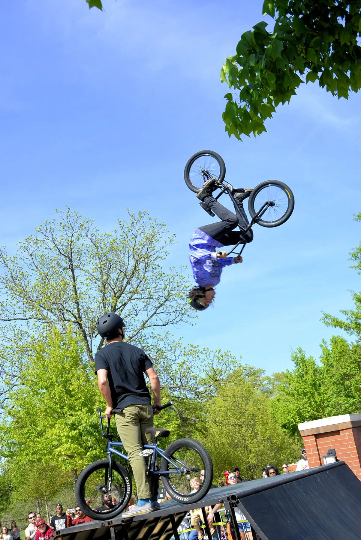 StuntDudes rider inverted off the ramp against a bright blue sky