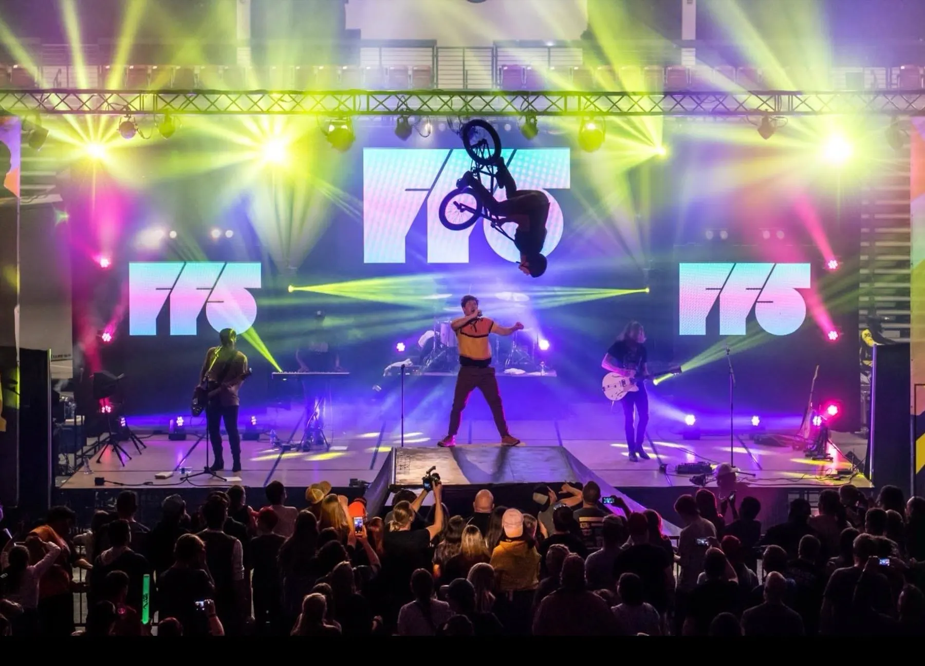 StuntDudes rider on a concert stage under purple lights and big screens