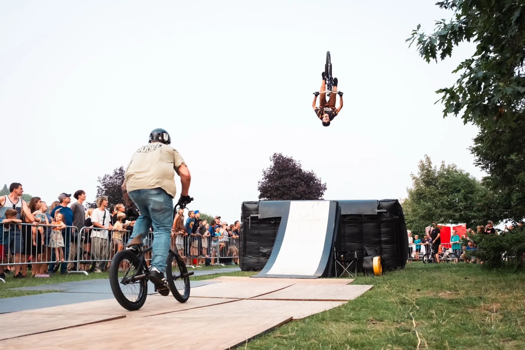 StuntDudes rider climbing the ramp as a teammate soars off the far one