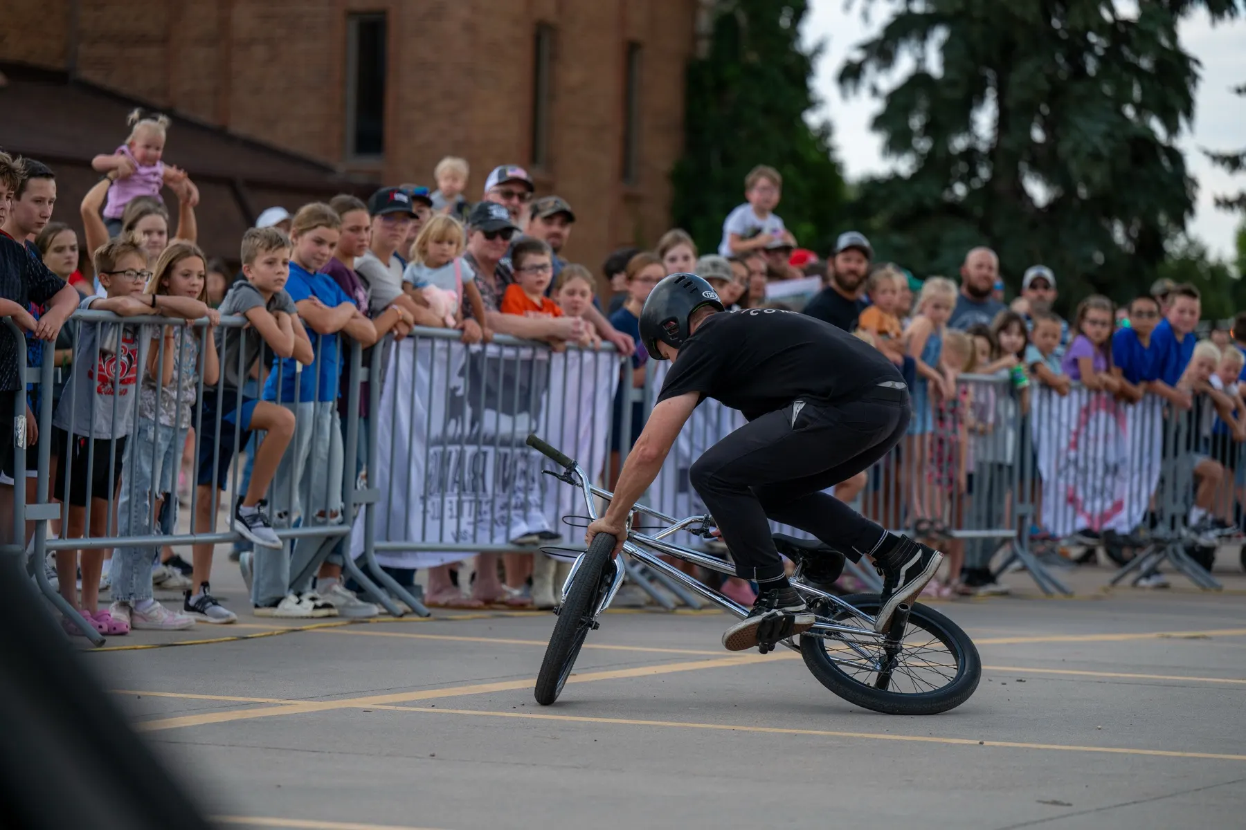 StuntDudes rider carving a trick in front of a barrier crowd at a downtown show
