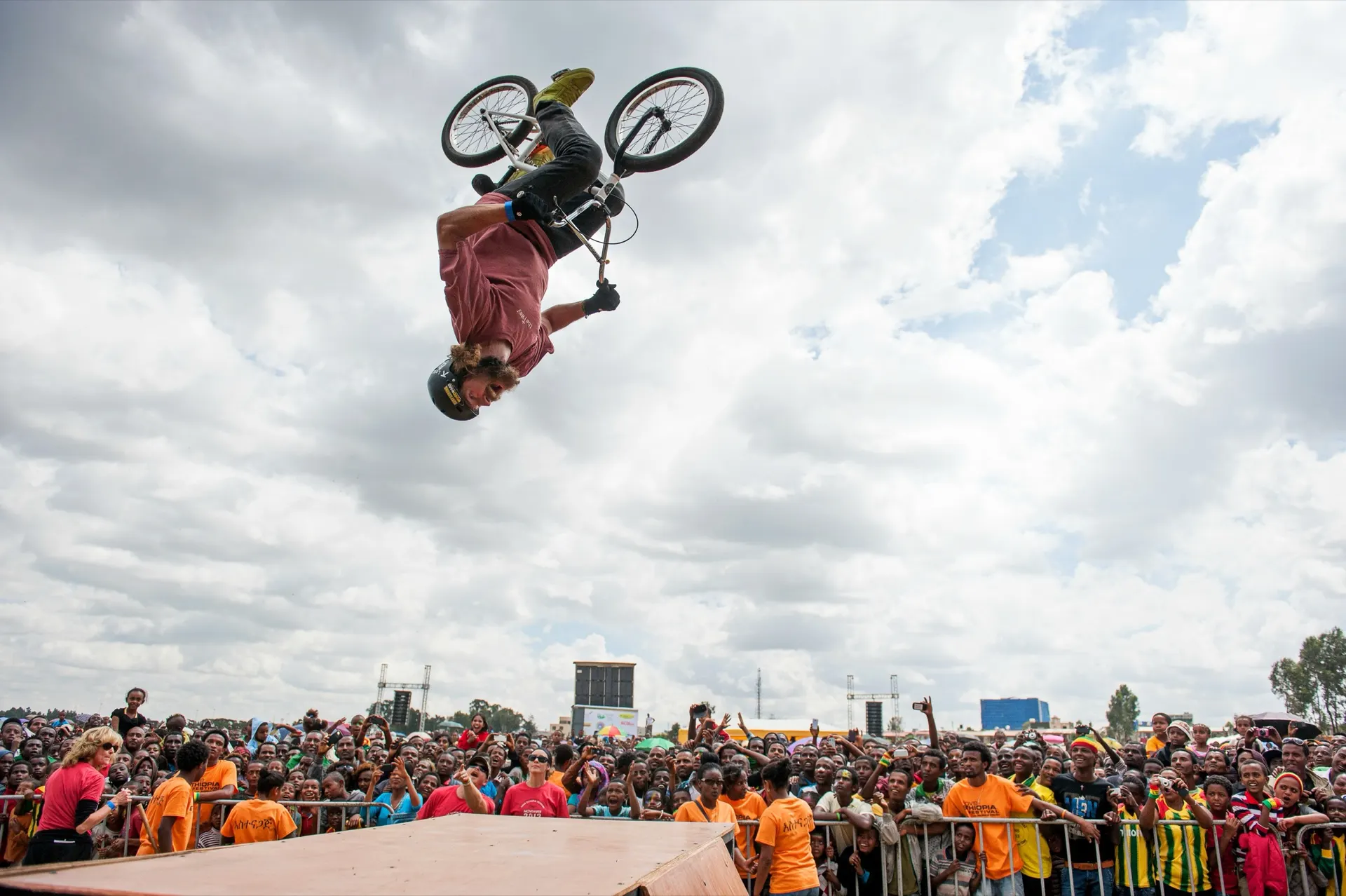 StuntDudes rider mid-backflip above a massive international crowd