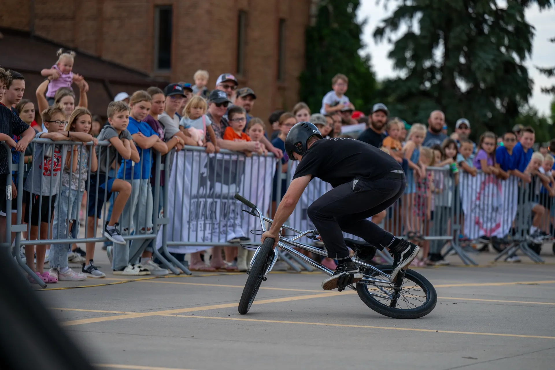 StuntDudes rider rolling a front-wheel trick feet from a crowd of kids