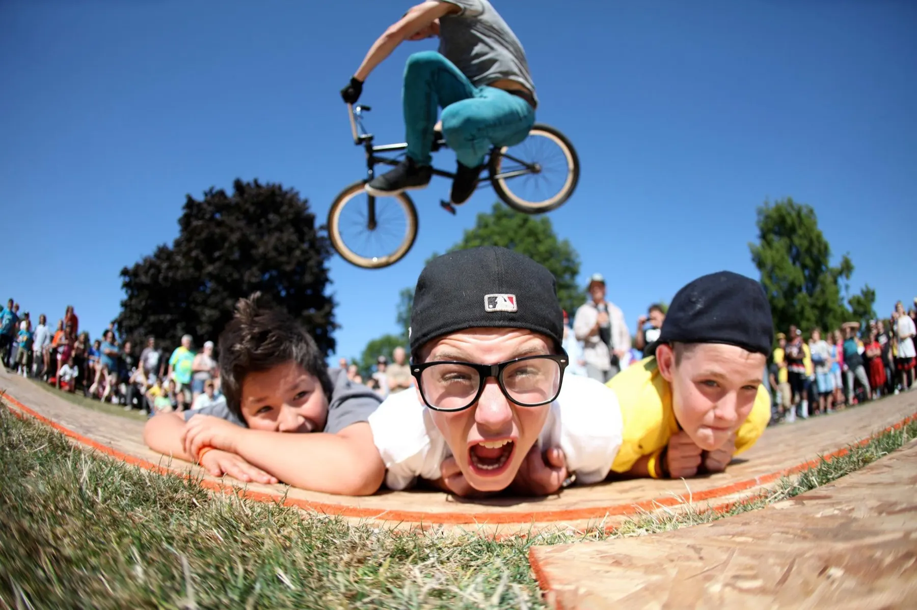 StuntDudes riders mugging for the camera as a teammate boosts air behind them